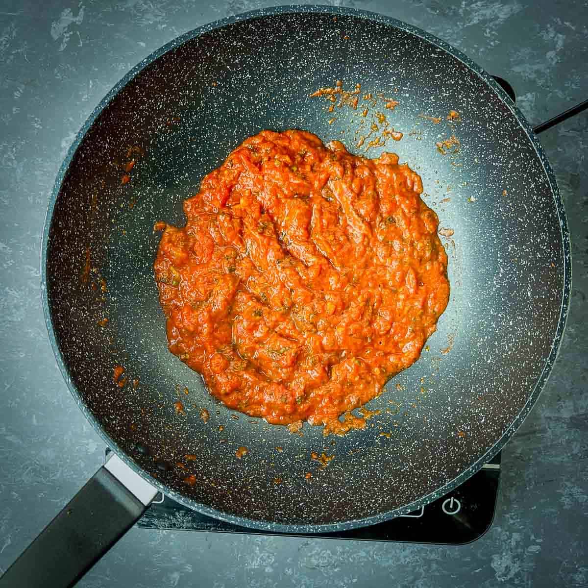 Cooked tomatoes and spices in a frying pan.