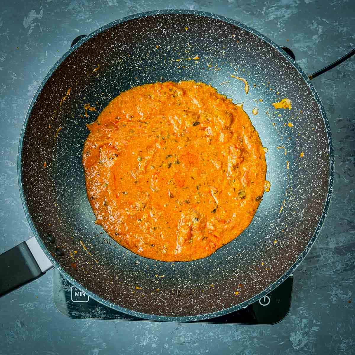 Cooked yogurt and tomato curry sauce in frying pan.