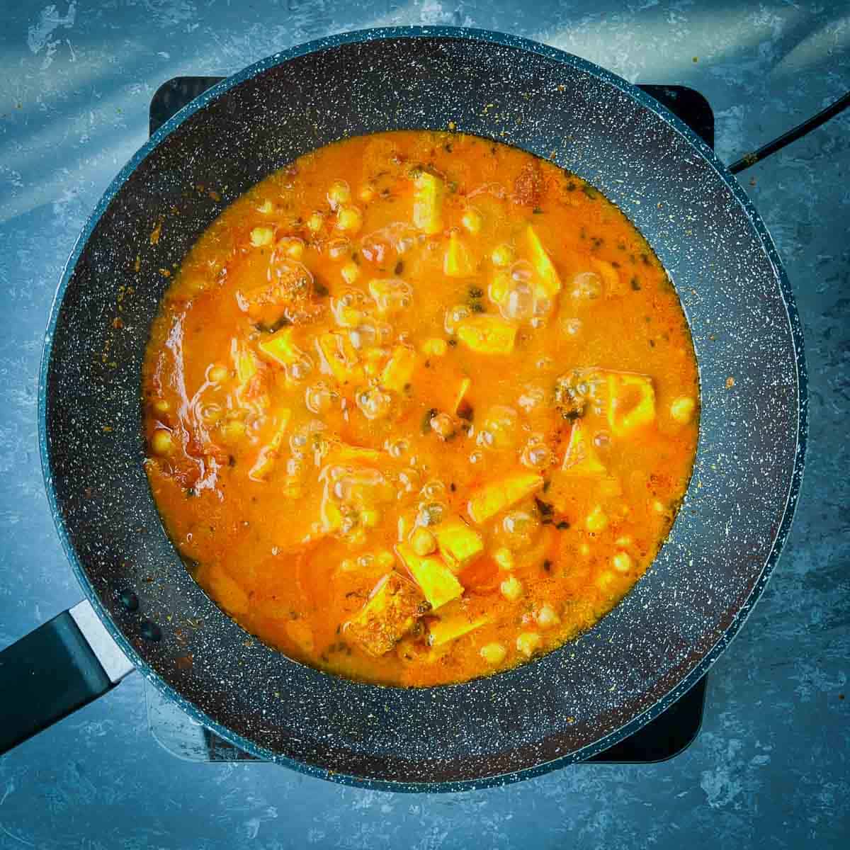 Chana paneer curry simmering in pan.