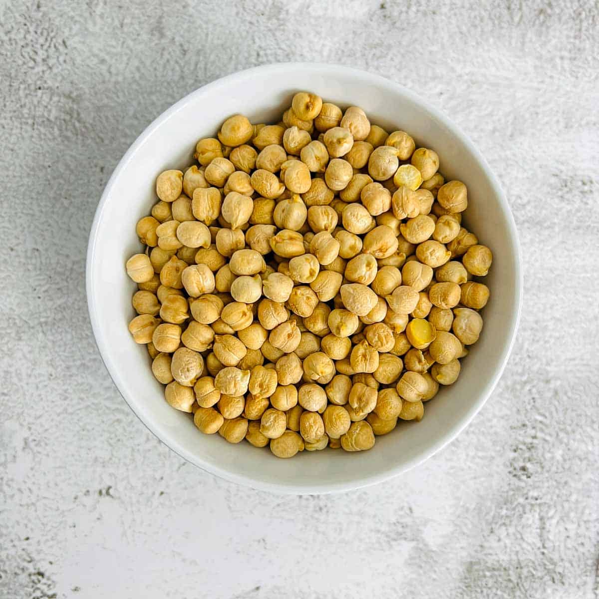 Dried chickpeas in a white bowl.