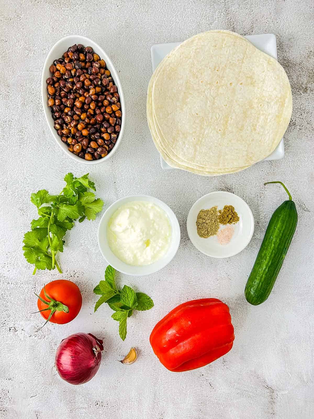 Ingredients to make black chickpea wraps placed on a white surface.