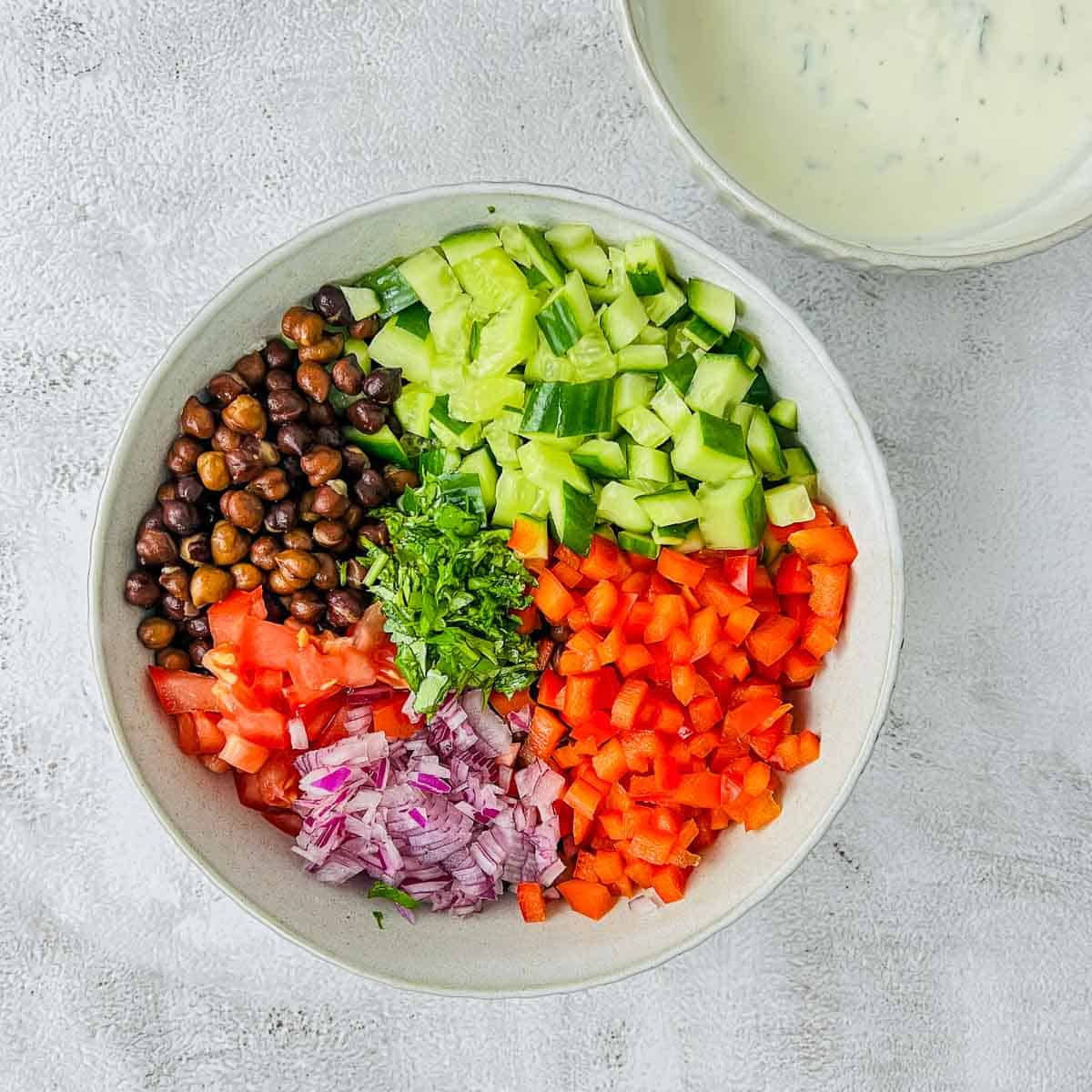 Boiled black chickpeas and veggies in a white bowl.