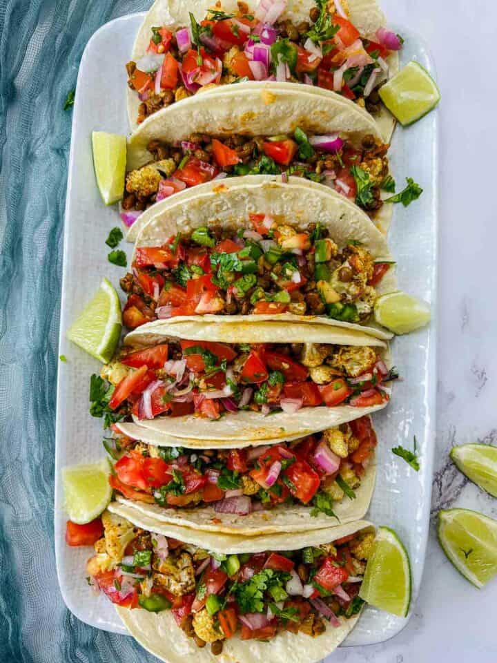 Cauliflower and lentil tacos on a white plate.