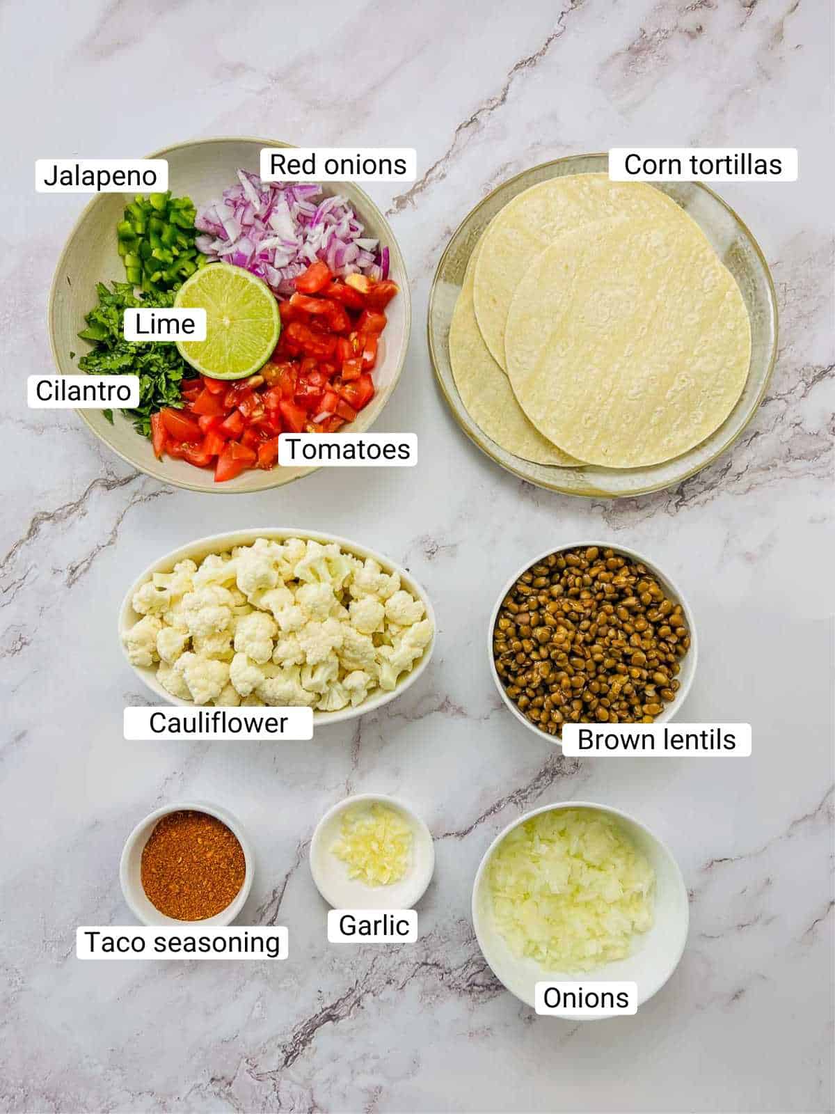 Ingredients to make cauliflower lentil tacos on a white surface.