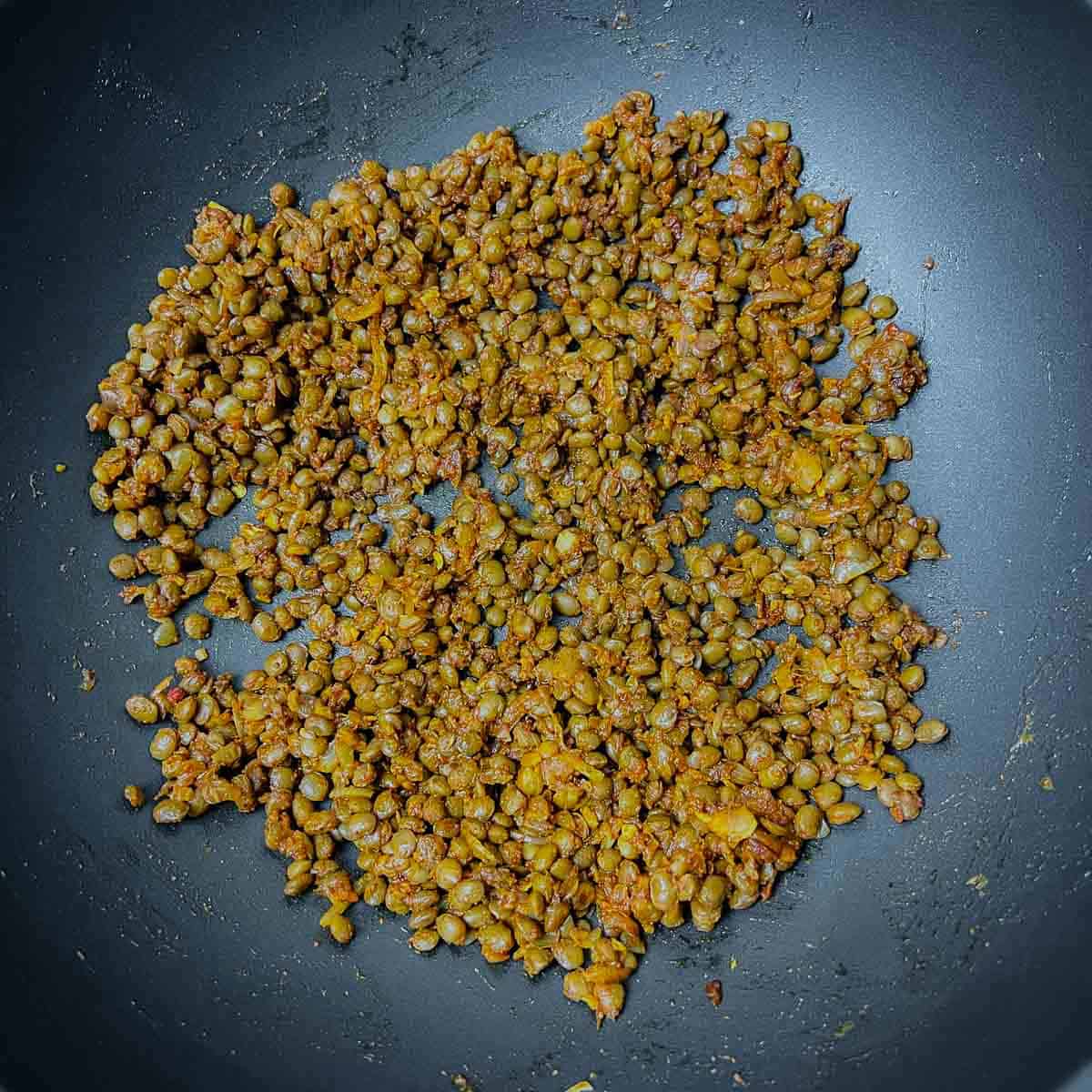 Toasted lentils and spices in a frying pan.