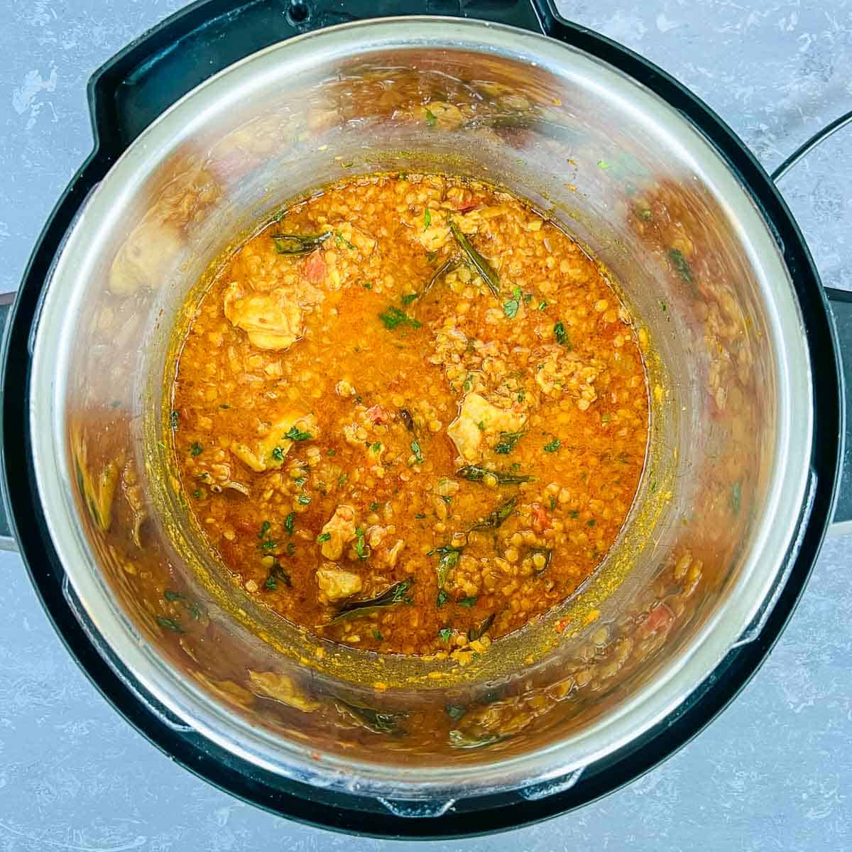 Pressure cooked chicken red lentil curry garnished with cilantro in Instant Pot.