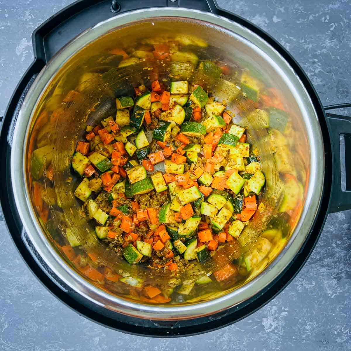 Sauted veggies and seasoning in Instant Pot.