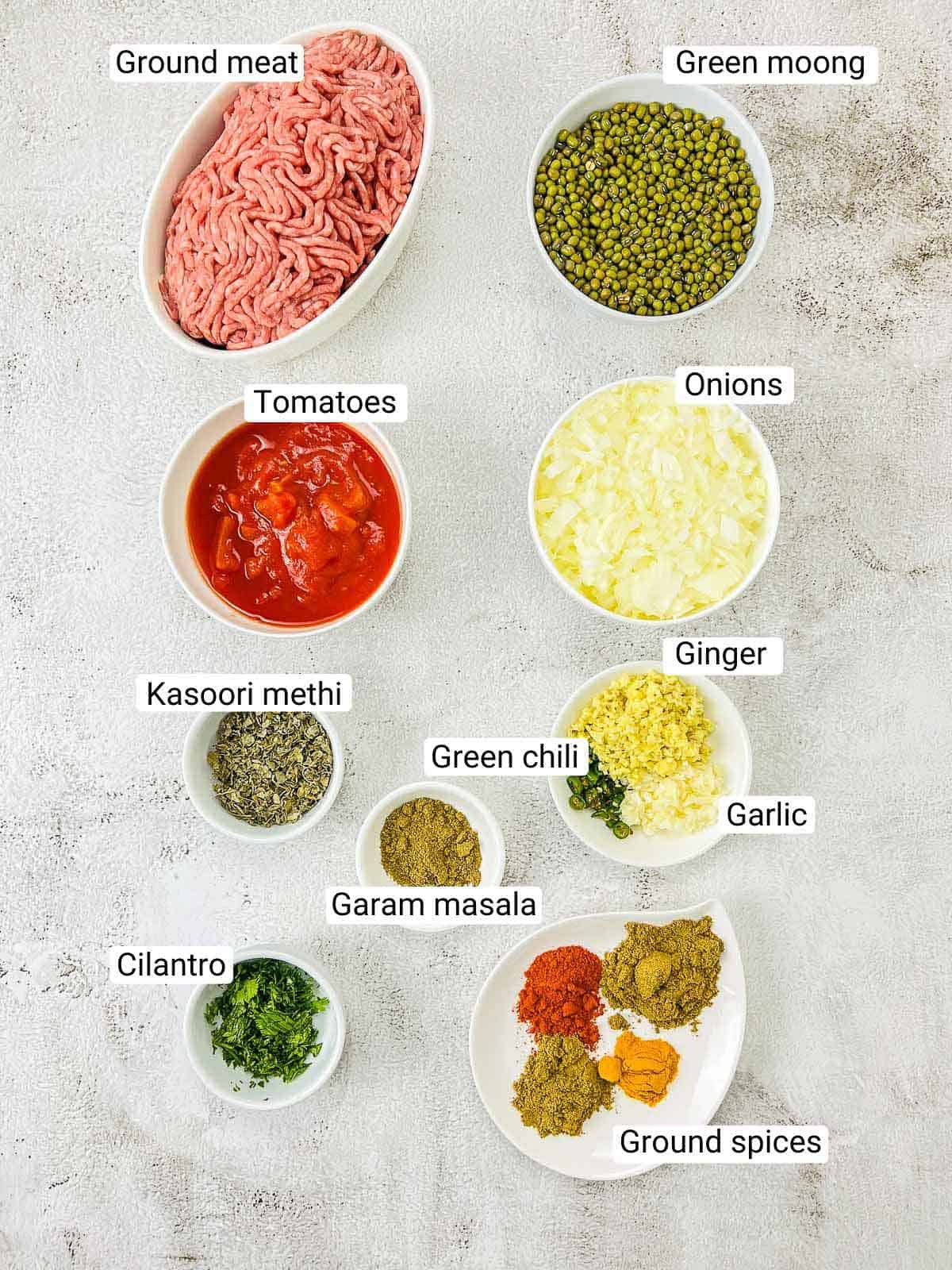 Ingredient to make keema green moong dal on a white surface.