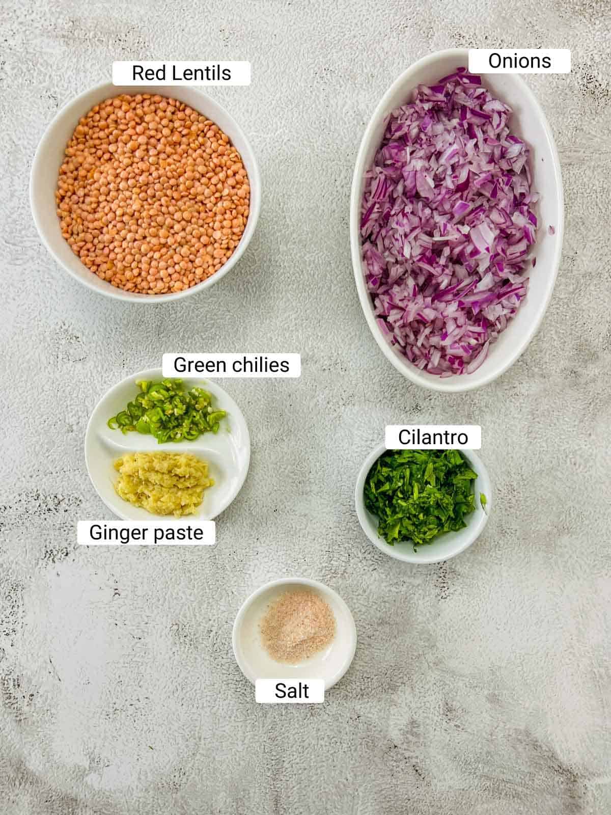 Ingredients to make red lentil fritters on a white surface.