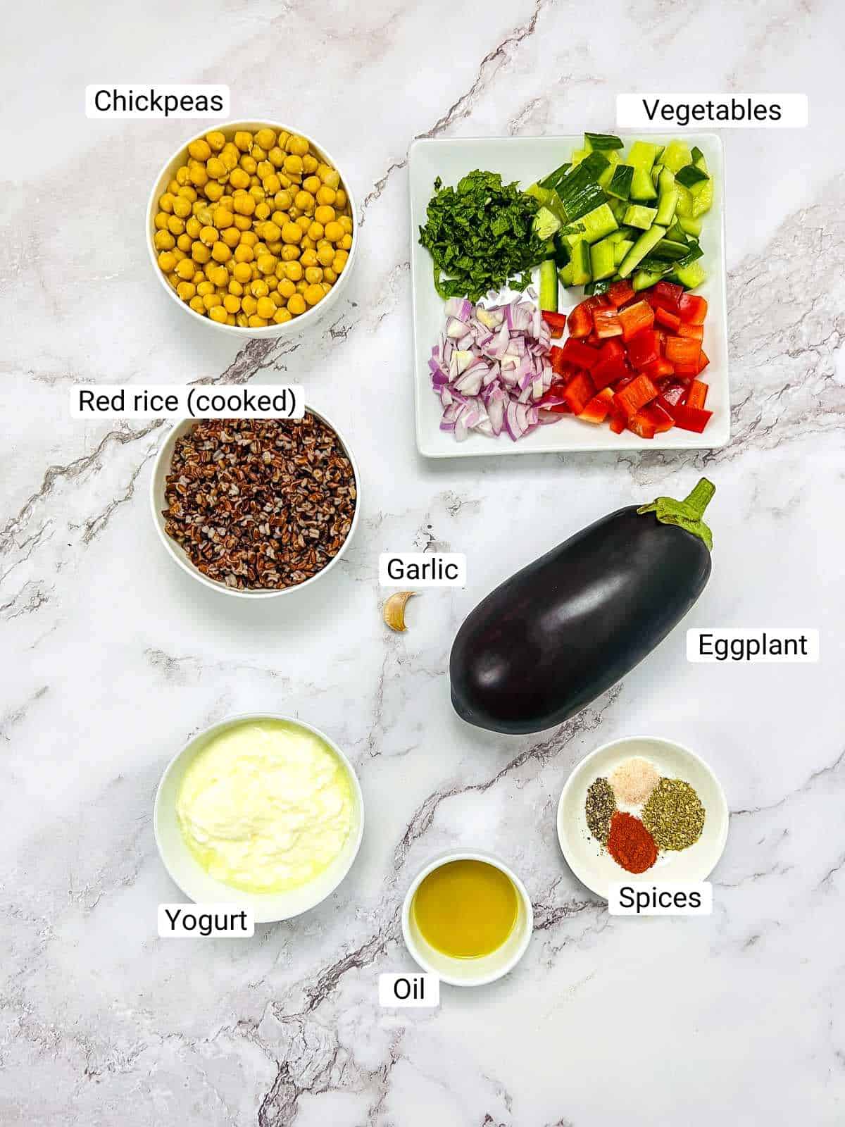 Ingredients to make eggplant chickpea buddha bowl on a white surface.