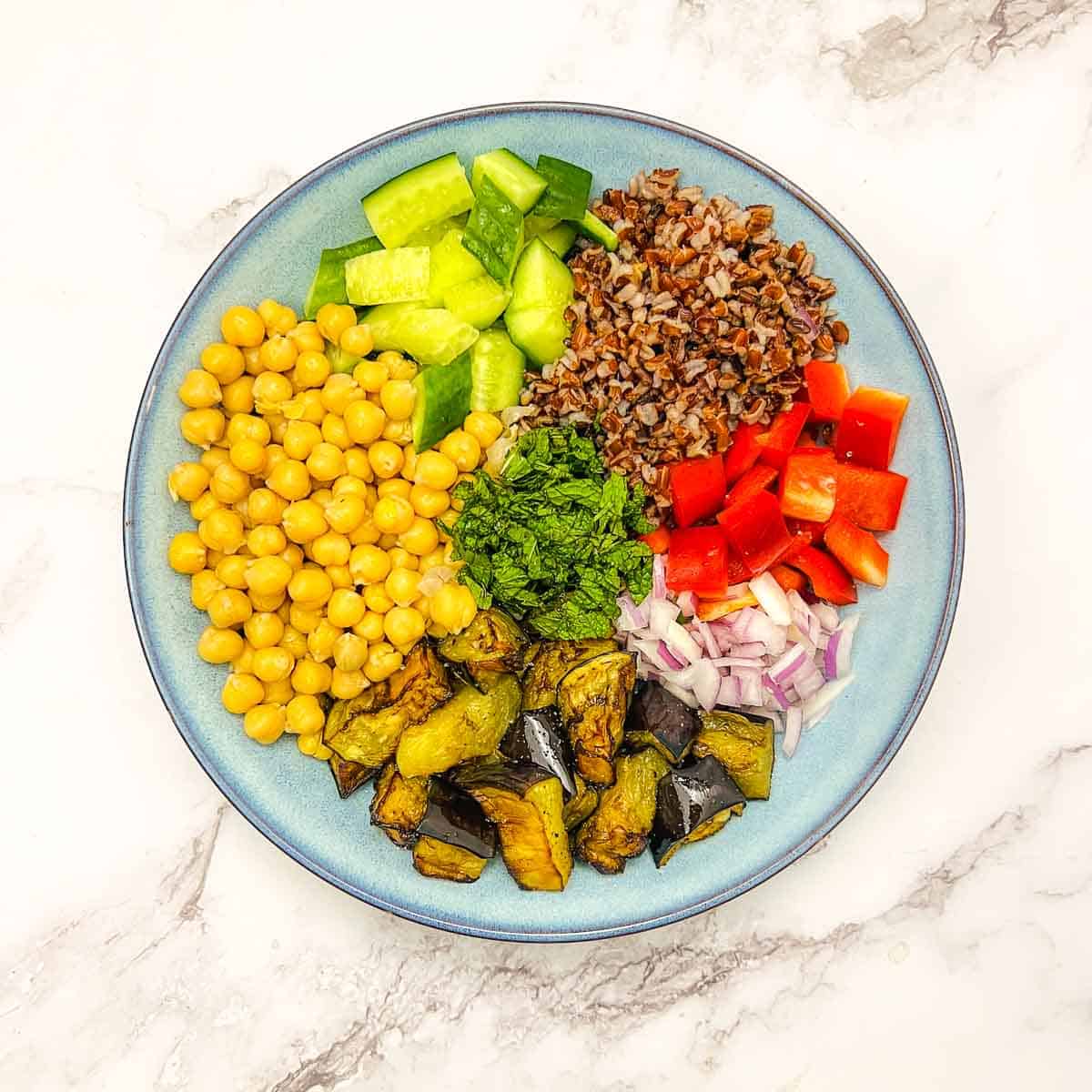 All components of Buddha bowl assembled in a blue bowl.