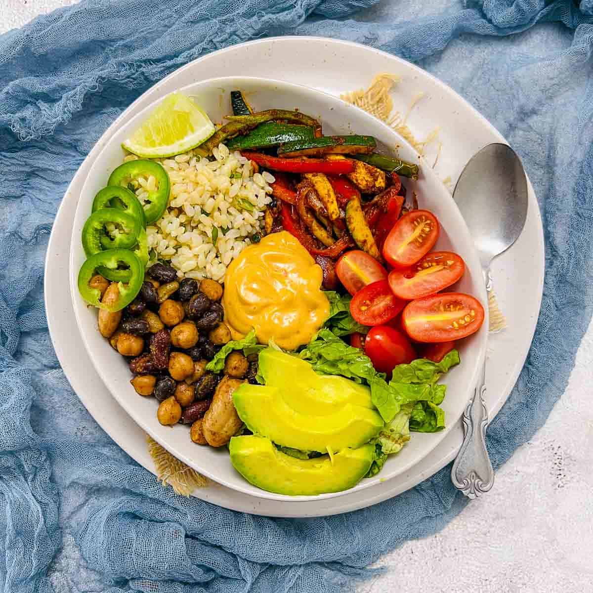 Taco Buddha bowl with mixed beans, cilantro rice, salad greens, and sauted veggies.