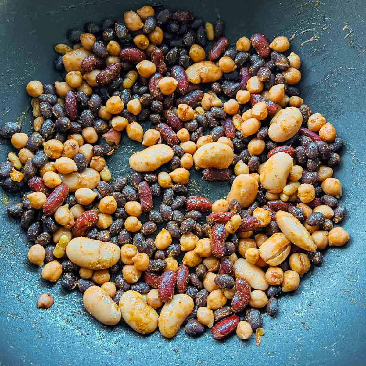 Mixed beans and seasoning toasted in a skillet.