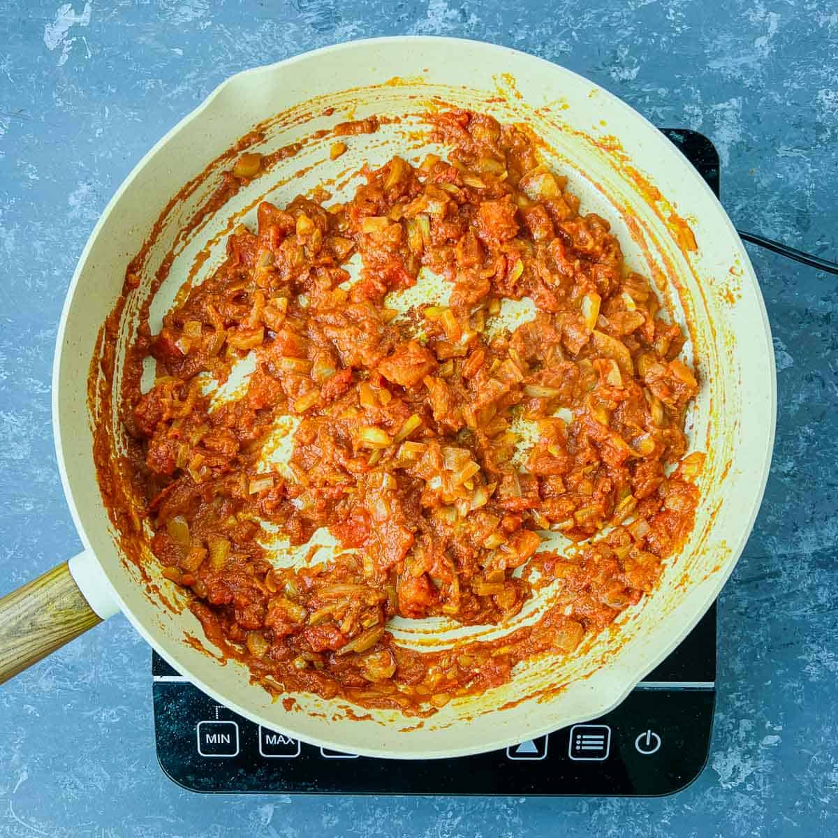 Cooked tomato and spices in a frying pan.