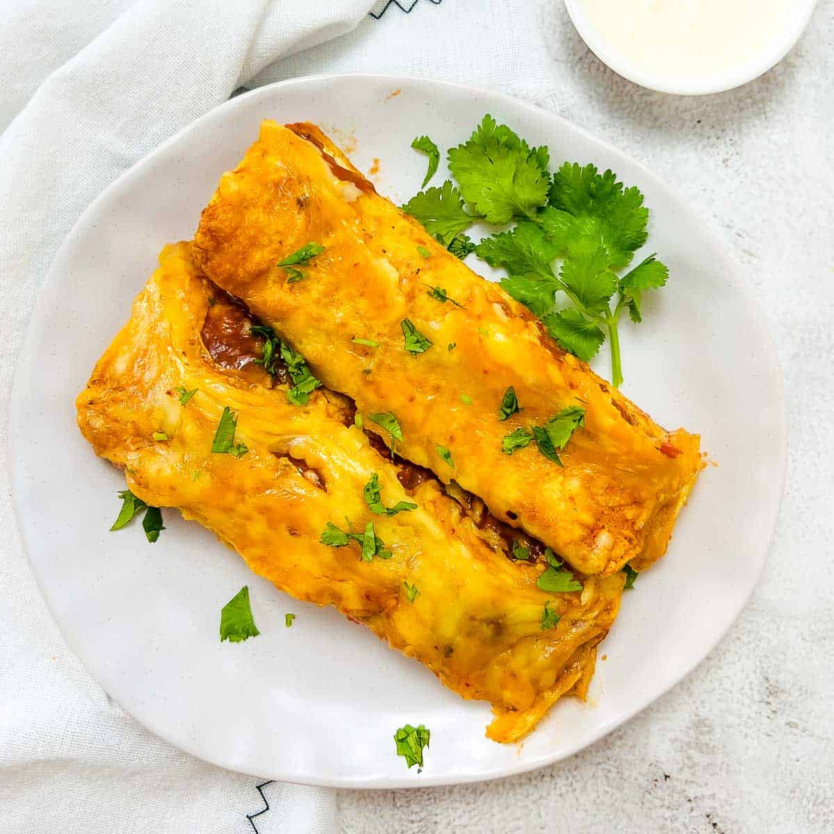 Chicken lentil enchiladas topped with cilantro and served with sour cream.