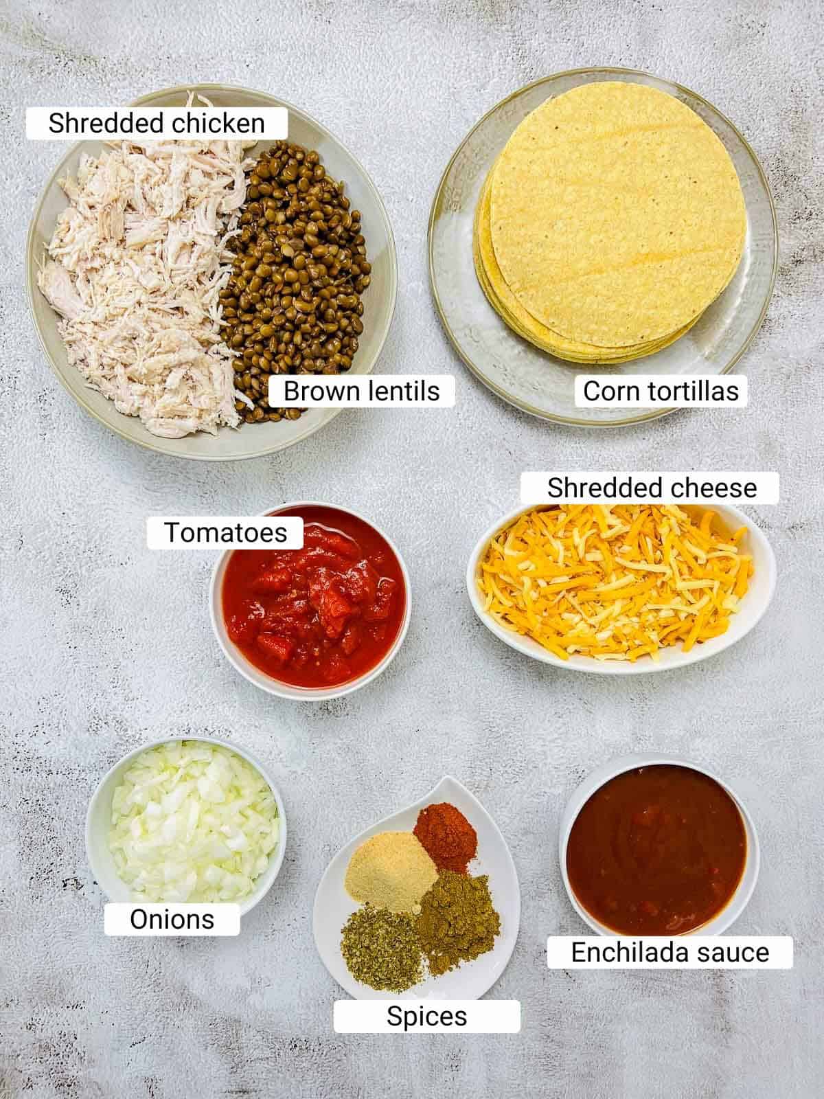 Ingredients to make chicken & lentil enchiladas on a white surface.