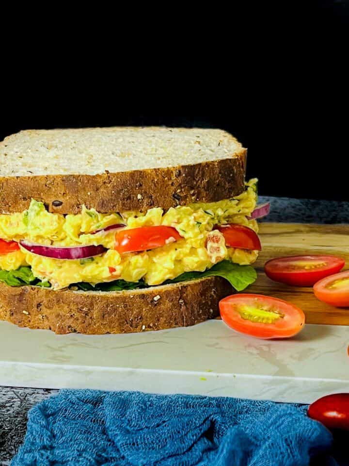 Chickpea salad sanwich with cherry tomatoes in the background.
