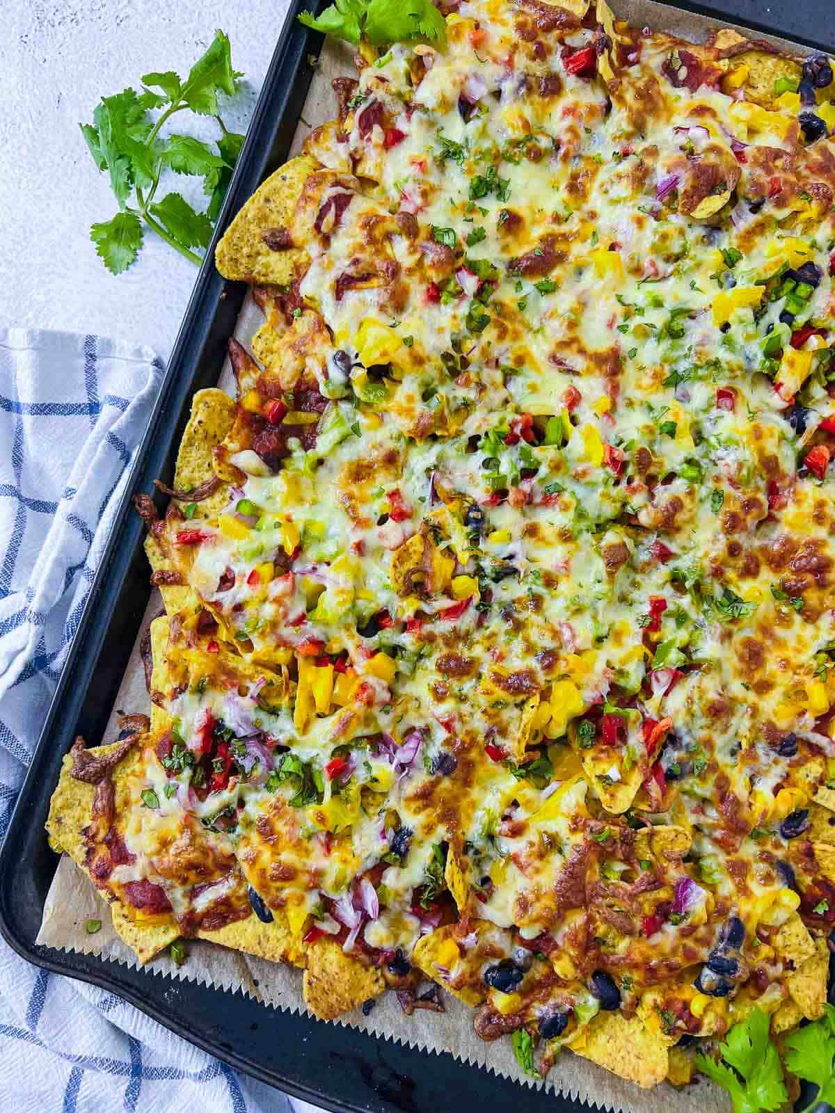 Loaded nachos in baking sheet topped with cilantro.