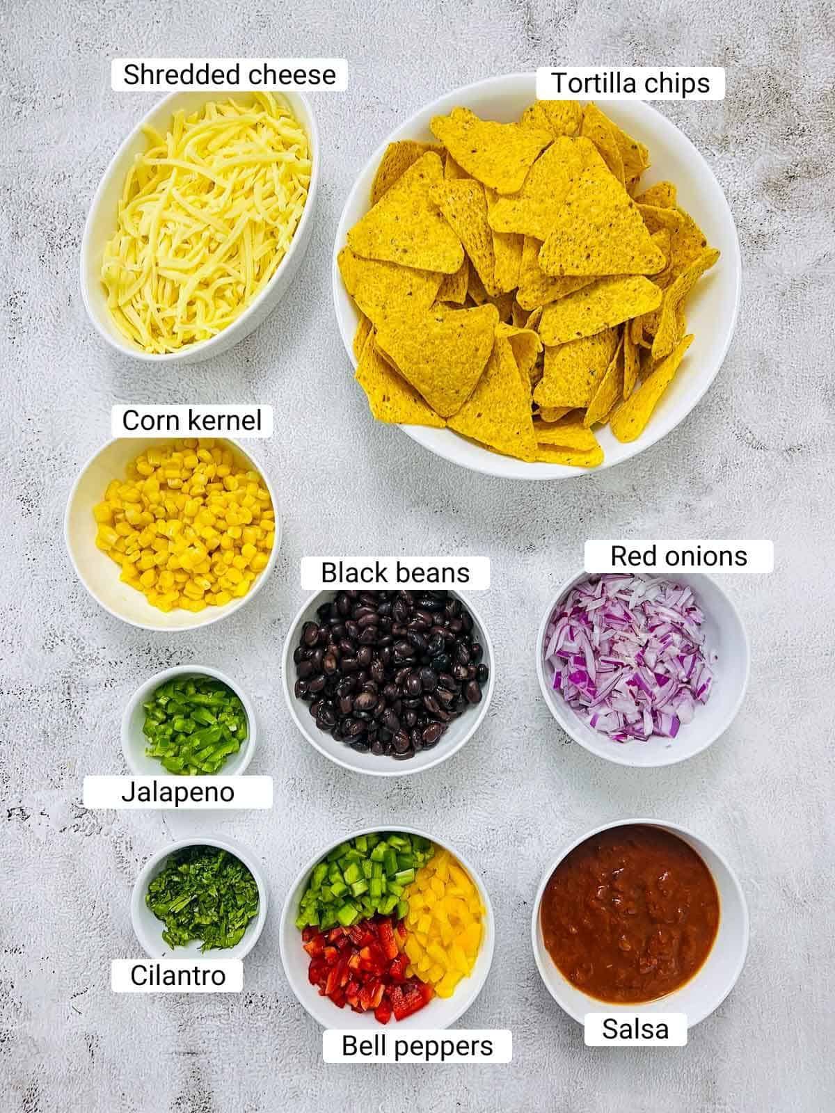Ingredients to make loaded nachos on a white surface.