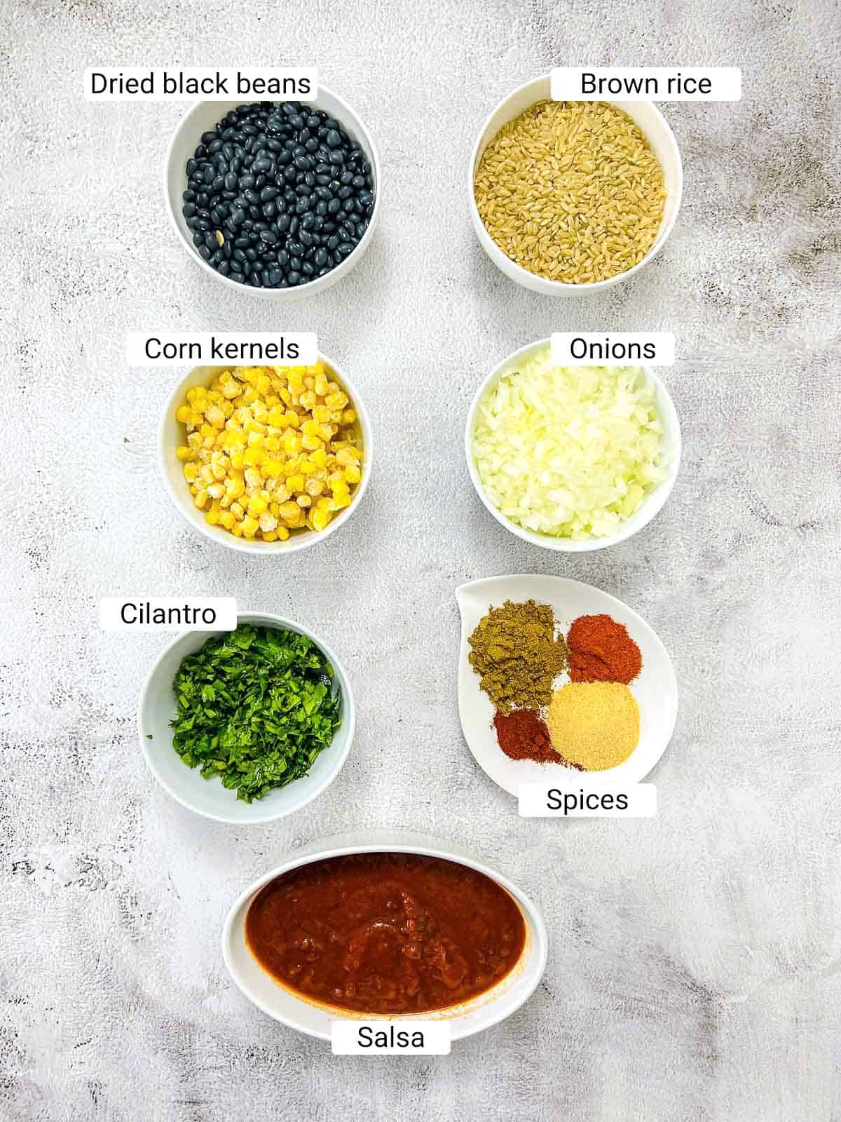 Ingredients to make Mexican rice and bean on a white surface.