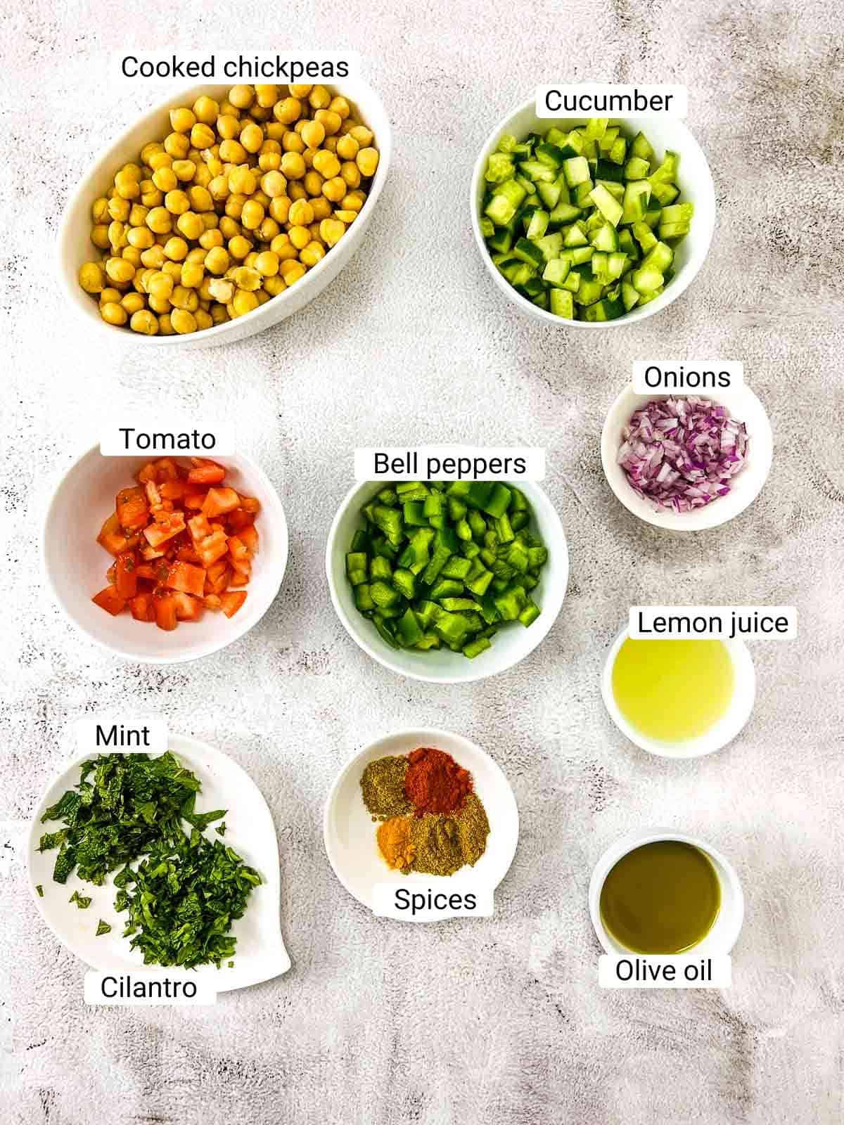 Ingredients to make chickpea salad on a white surface.
