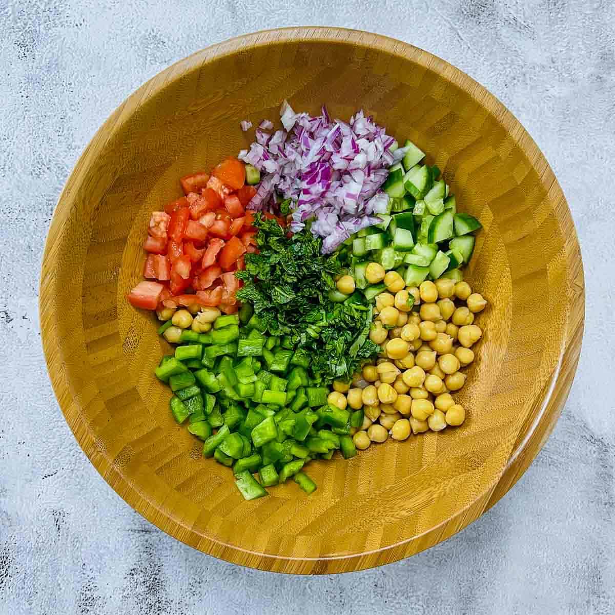 Chickpeas and rainbow veggies in a salad mixing bowl.