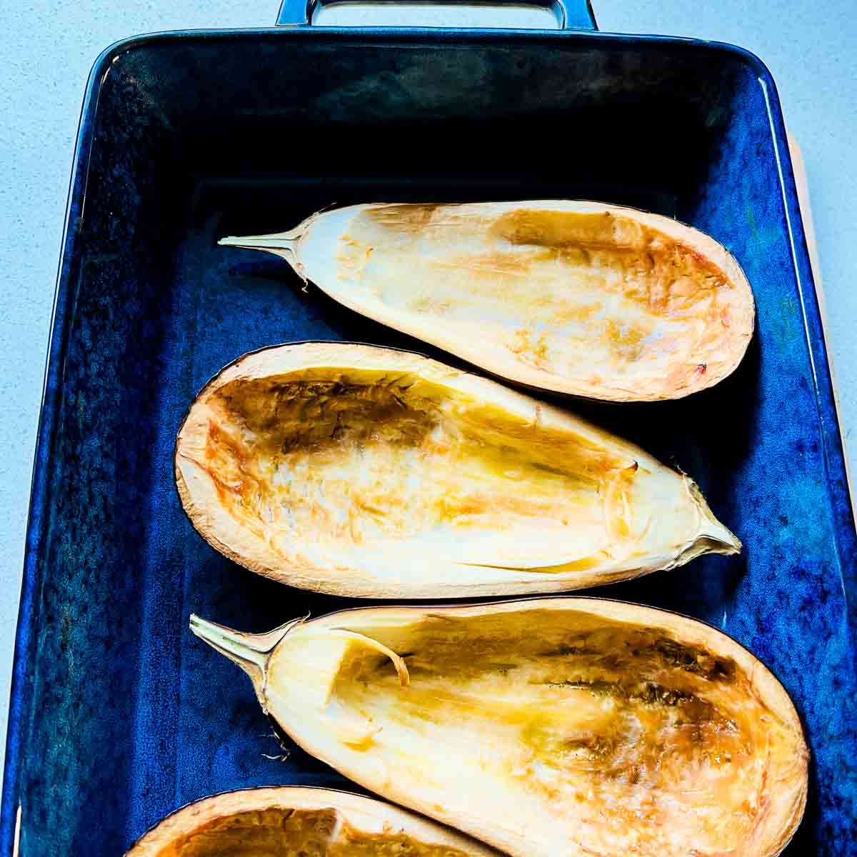 Prepared eggplants roasted in a baking dish.