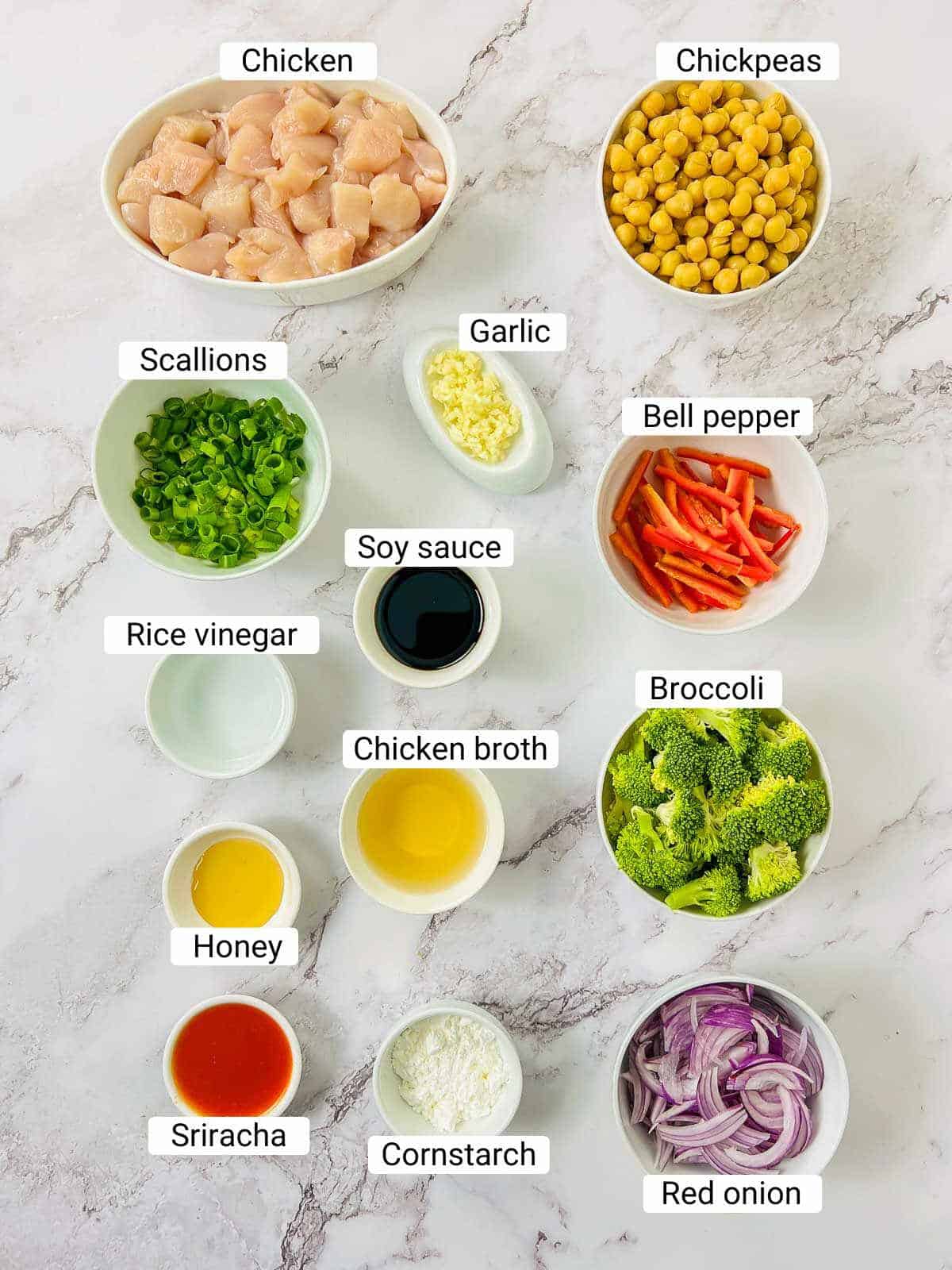 Ingredients to make chicken chickpeas stir fry on a white surface.