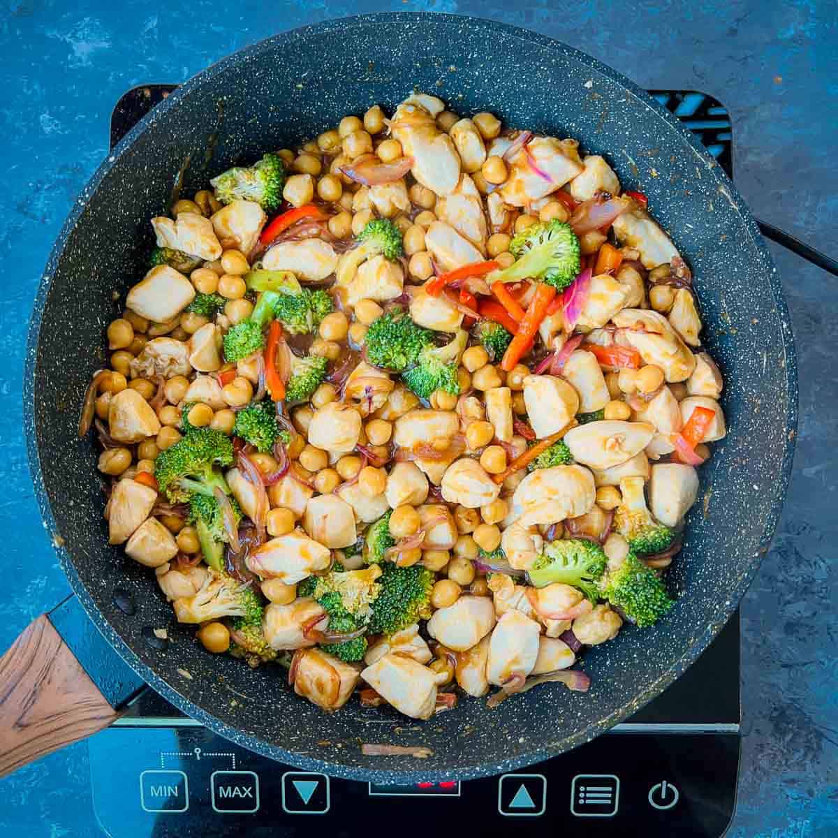 Chicken, chickpeas, and sauce in frying pan.
