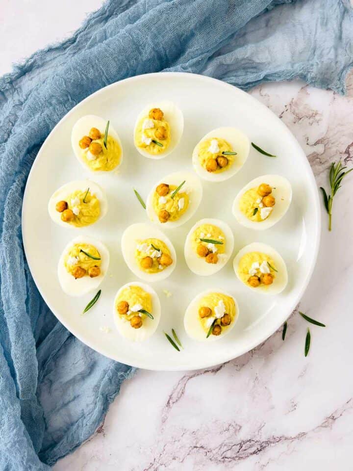 Deviled eggs with chickpeas on a white plate.