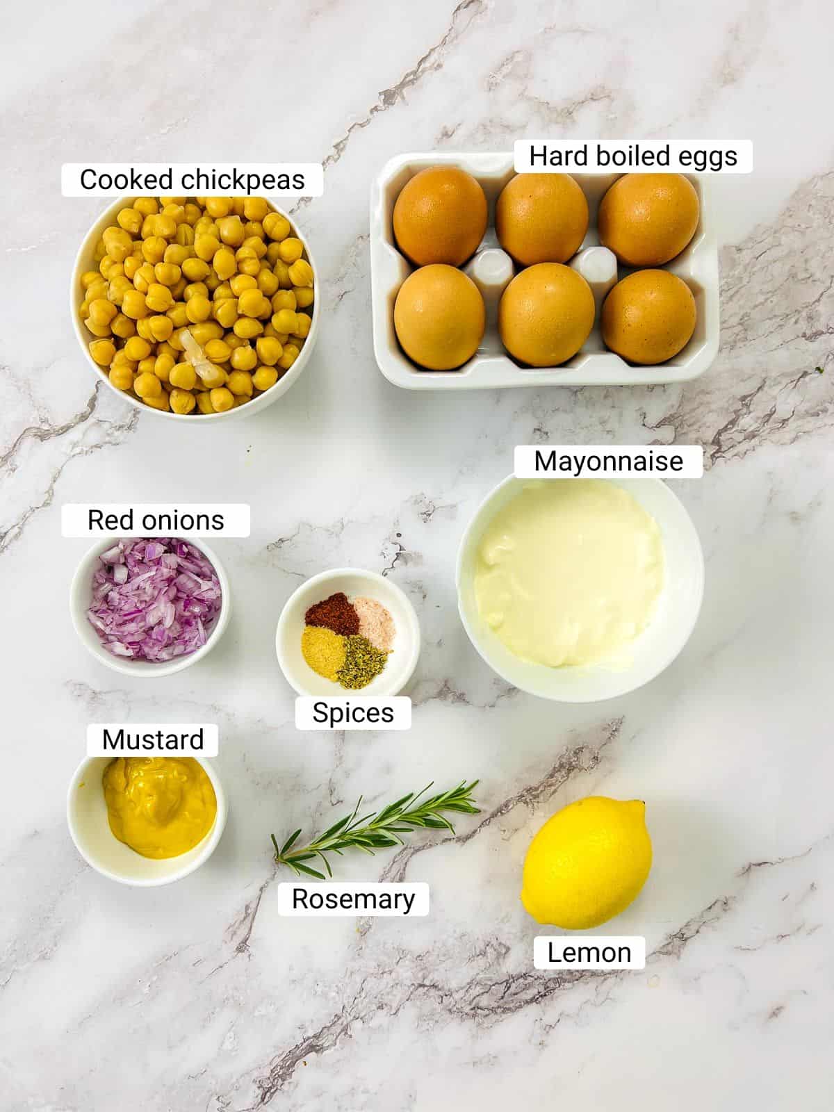 Ingredients to make deviled eggs with chickpeas on a white surface.