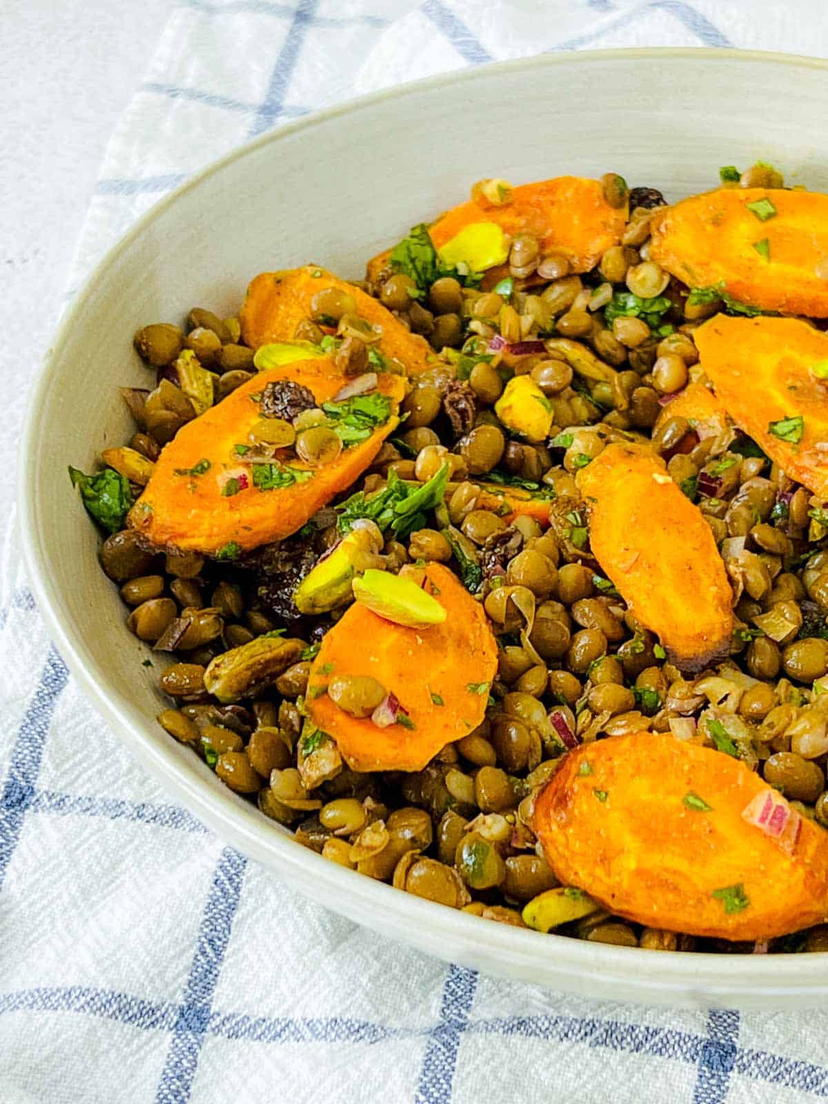 Lentil carrot salad topped with pistachio and cilantro.