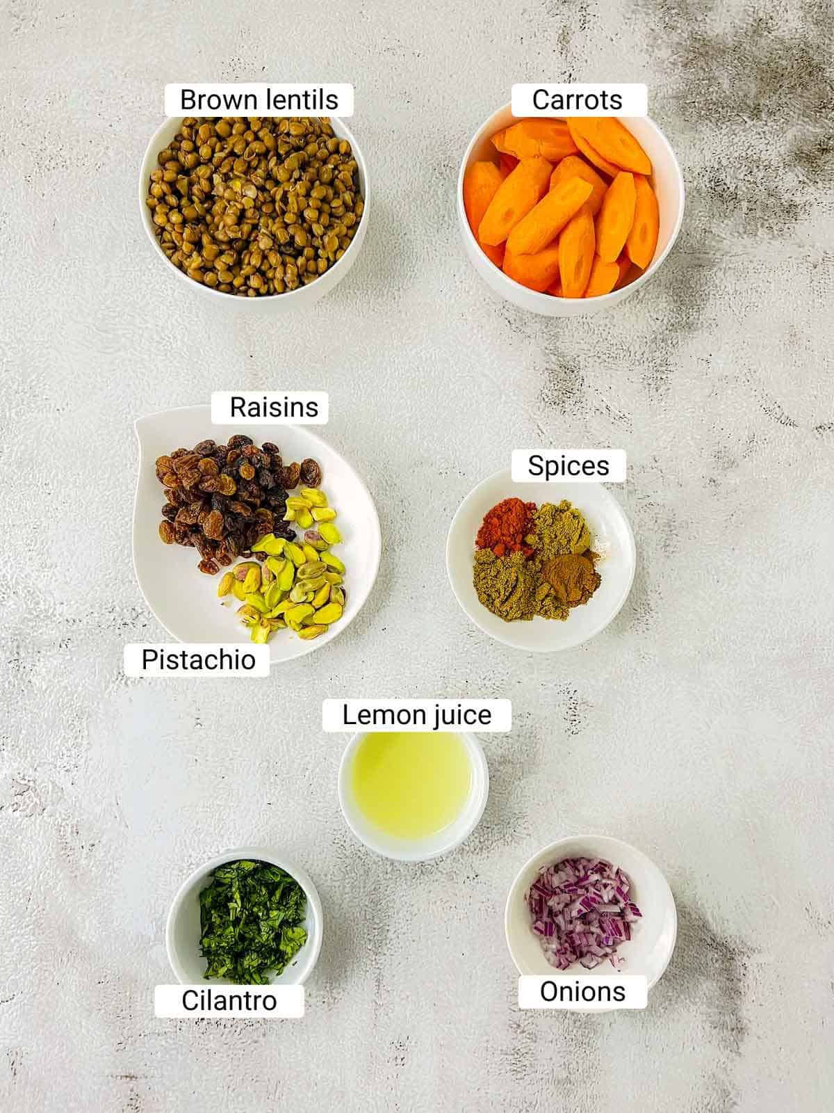 Ingredients to make Moroccan lentil and carrot salad on a white surface.