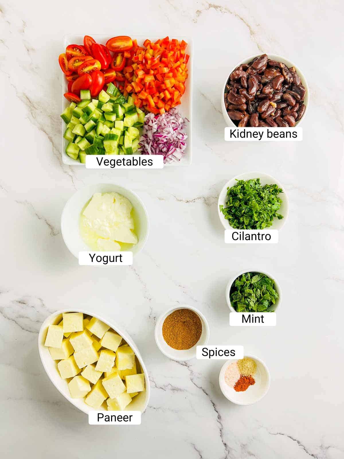 Ingredients to make paneer rajma salad on a white surface.
