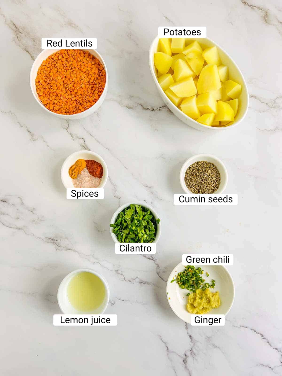Ingredients to make red lentil pancakes with potatoes on a white surface.