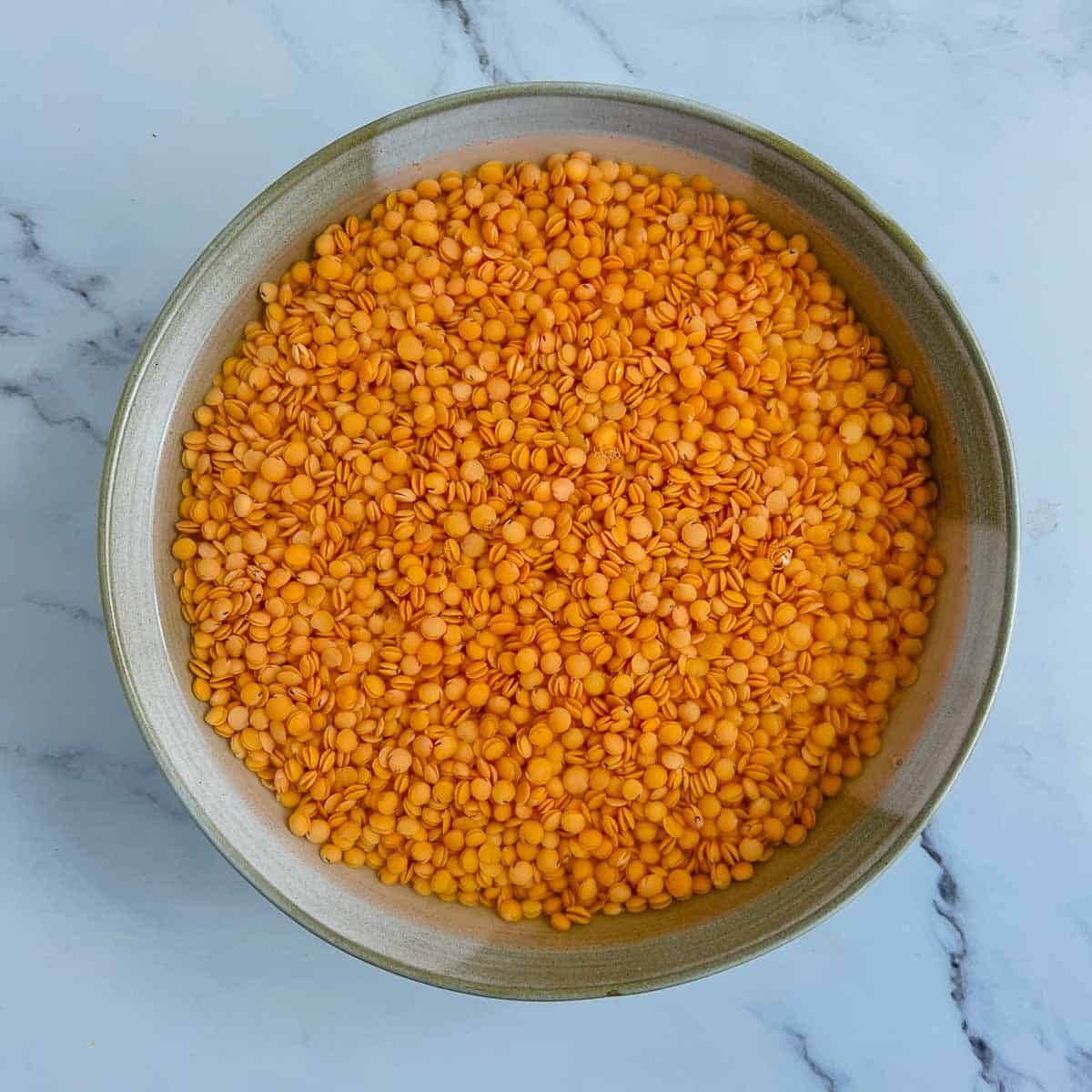 Soaked red lentils in a wide bowl.