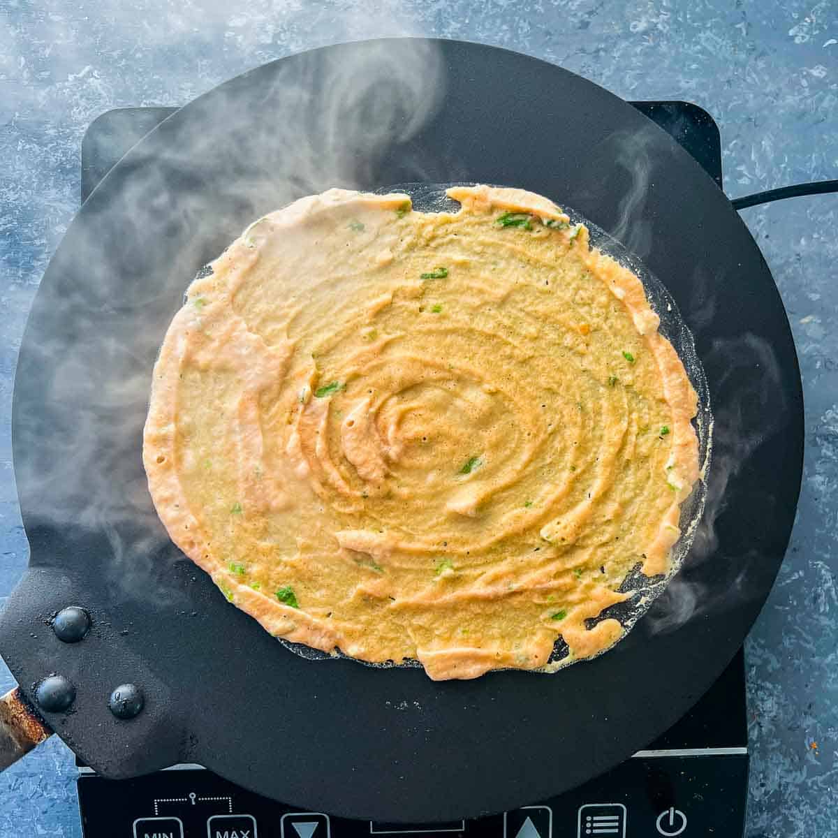 Pancake batter poured on hot tawa/griddle.