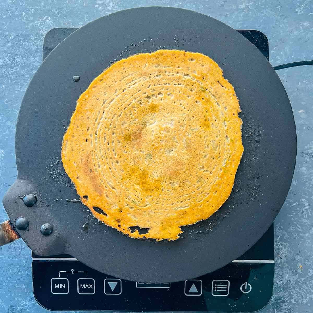 Pancake flipped on tawa and cook on both sides.