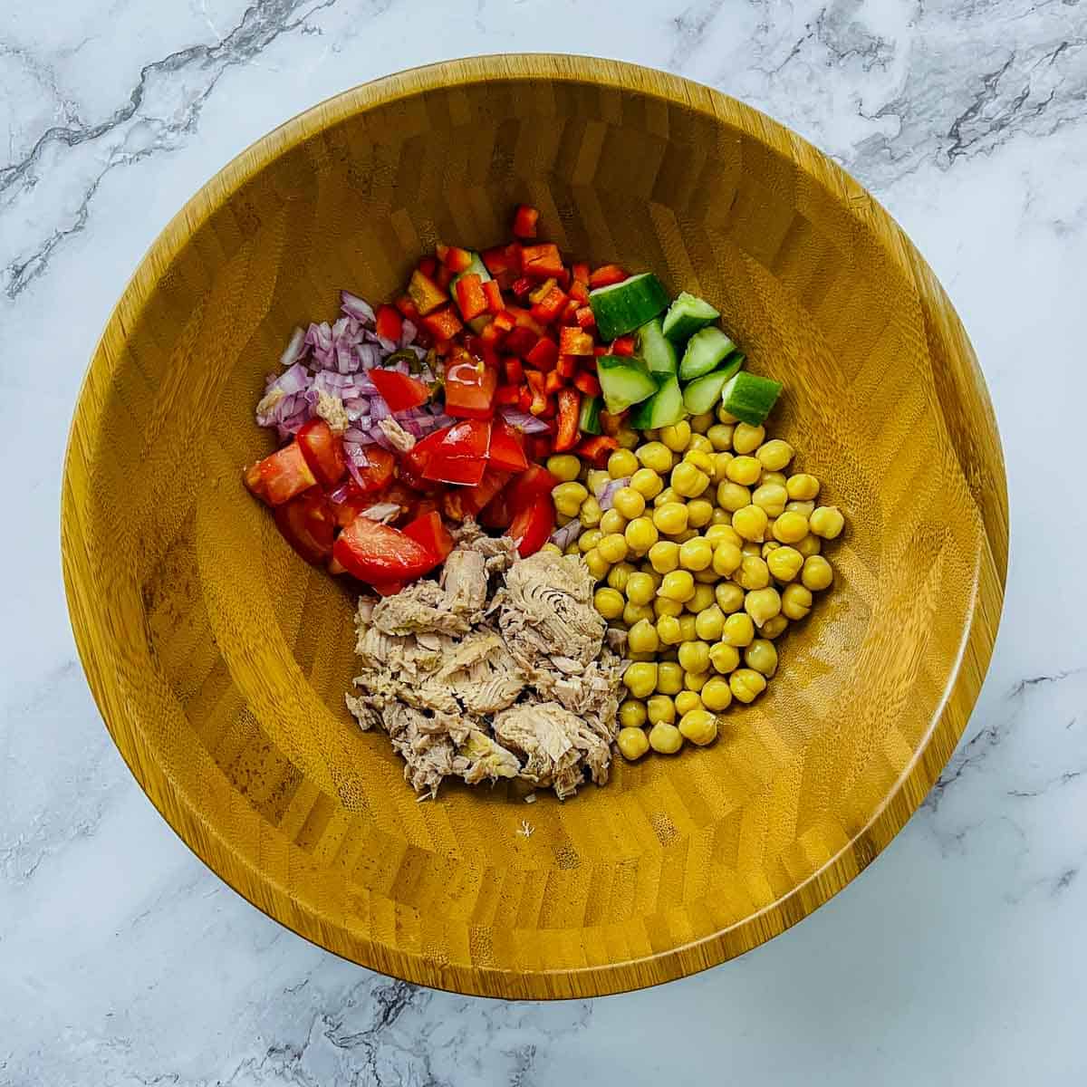 Tuna, chickpea, and salad veggies in a mixing bowl.