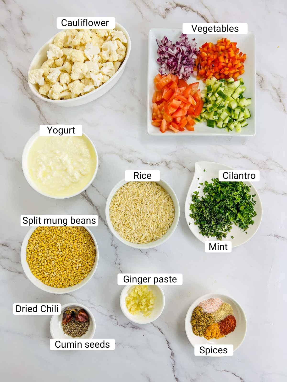 Ingredients to make yellow lentil Buddha bowl on a white surface.