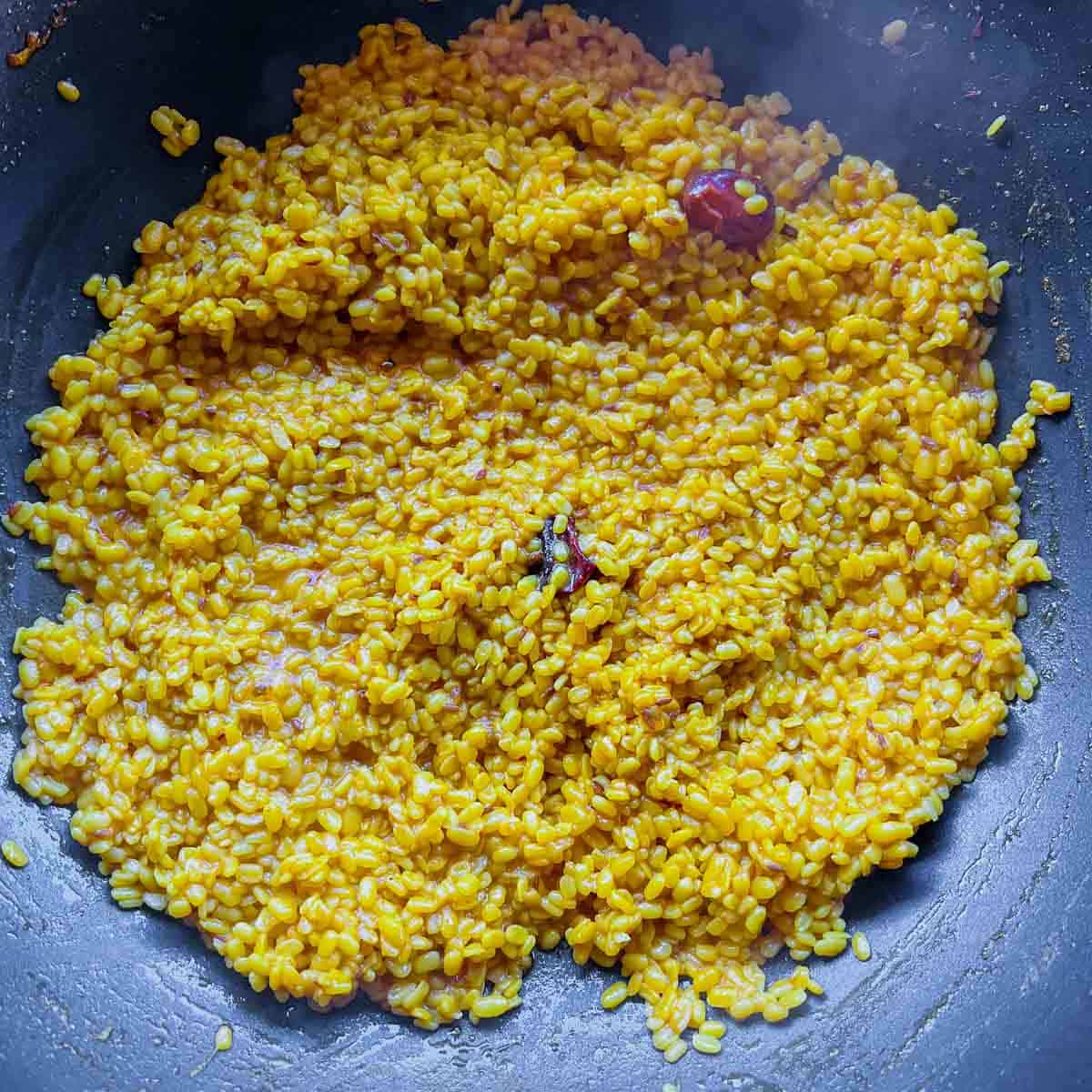 Tempering and yellow lentils in frying pan.