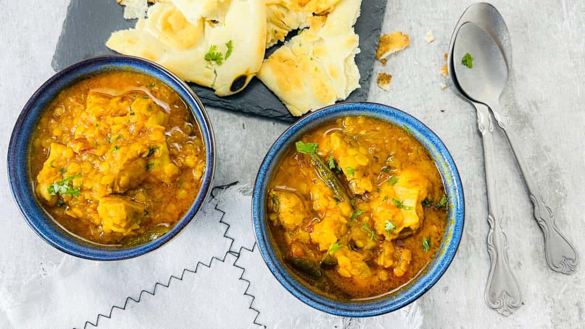 Chicken lentil curry in blue bowls served with naan bread.