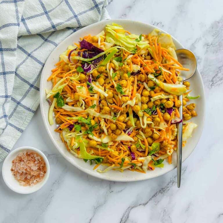Roasted chickpea crunch salad on a white plate with a serving spoon.