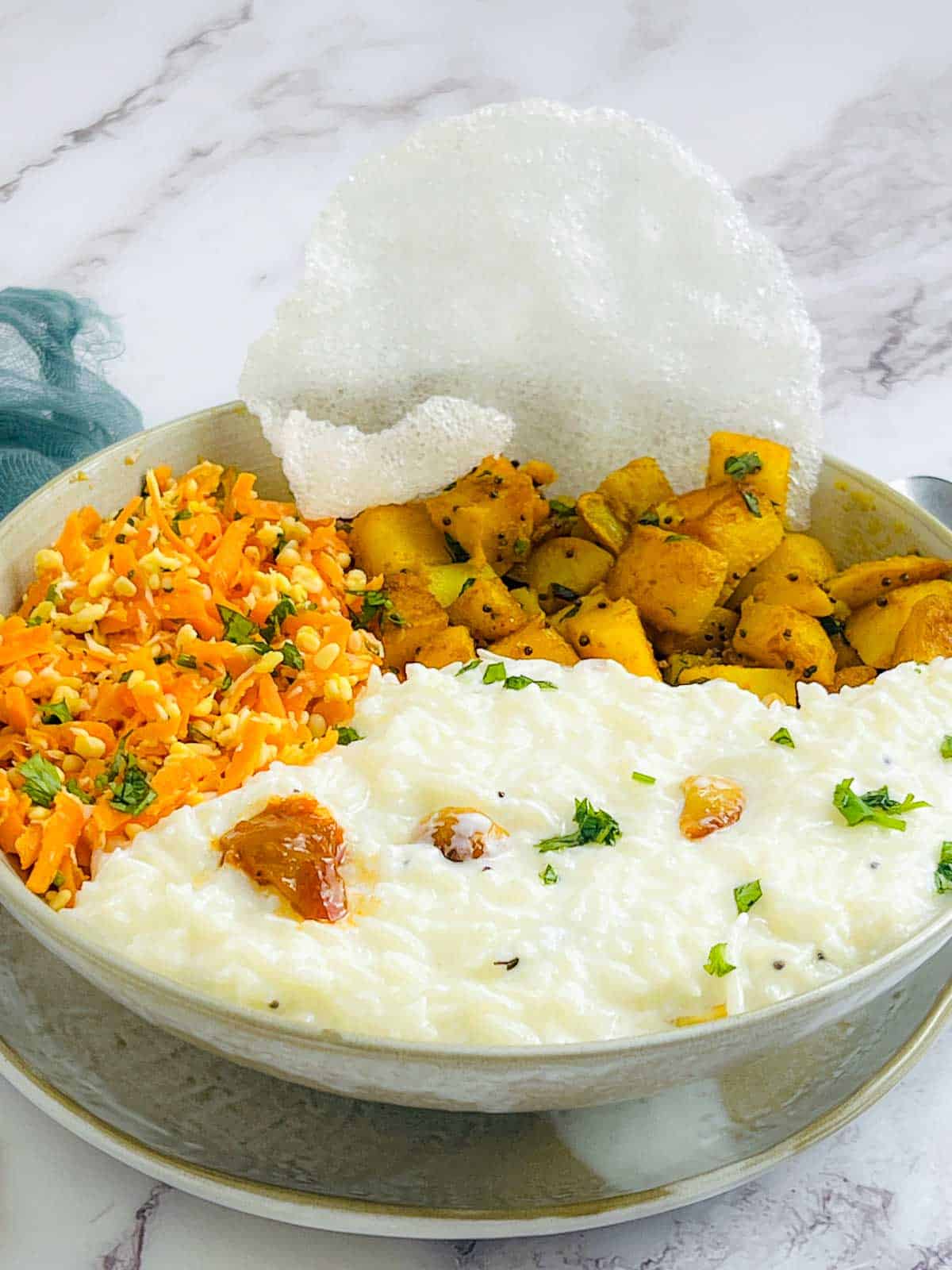 Curd rice bowl topped with papad and pickle.