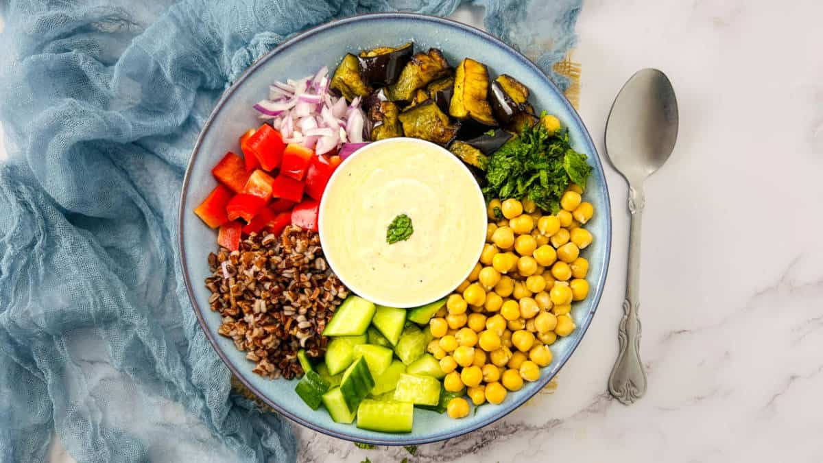 Eggplant and chickpea Buddha bowl on a white surface.