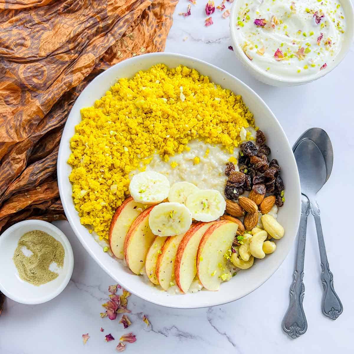 Indian oatmeal breakfast bowl topped with besan laddu crumble.