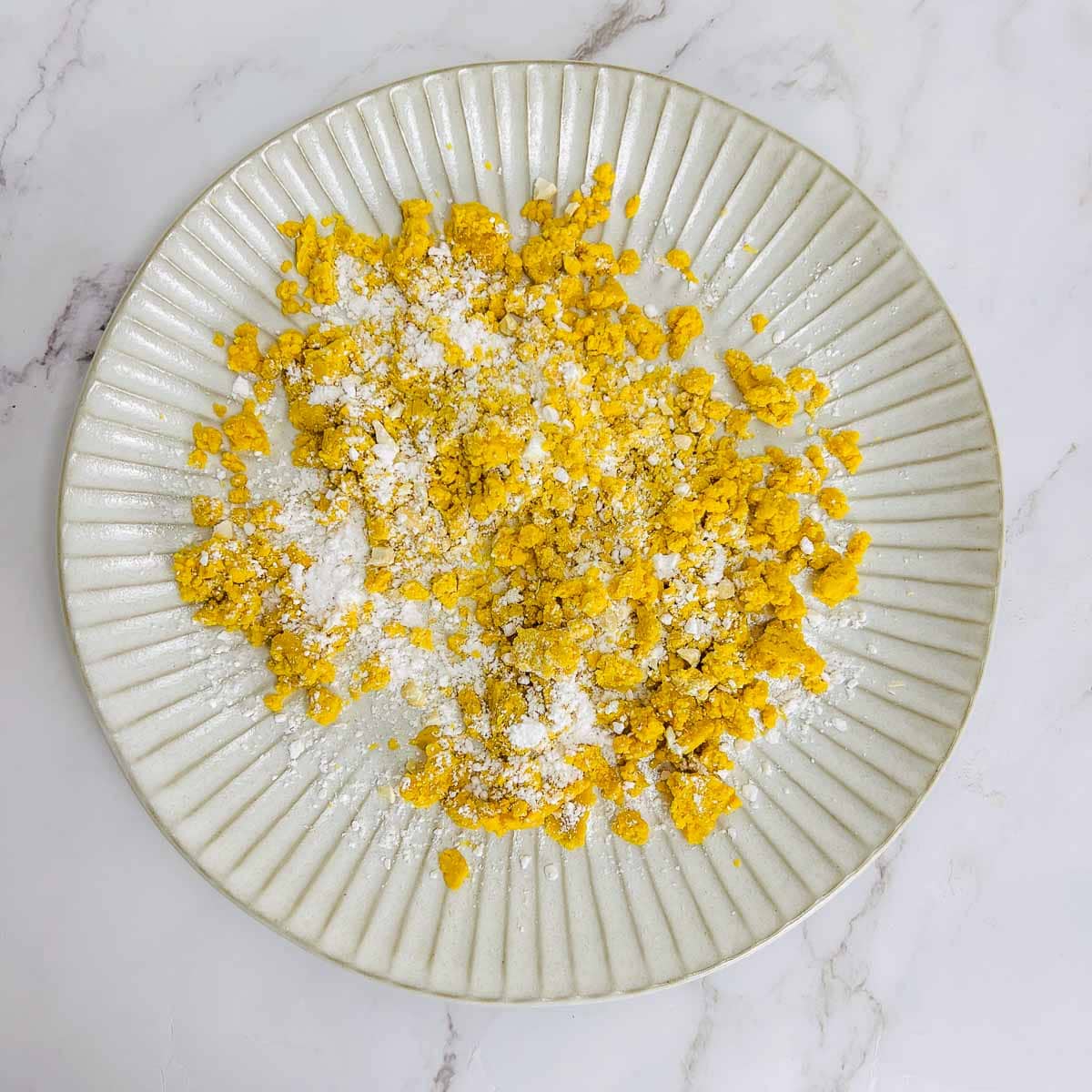 Roasted chickpea flour mixed with sugar in a white plate.