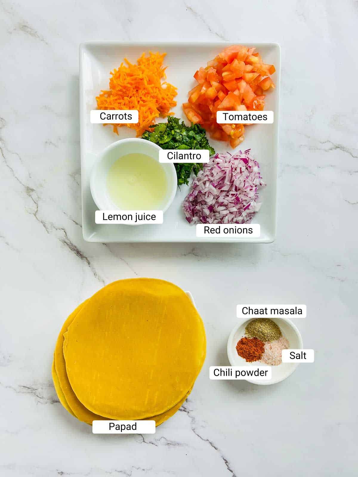 Ingredients to make masala papad on a marble surface.