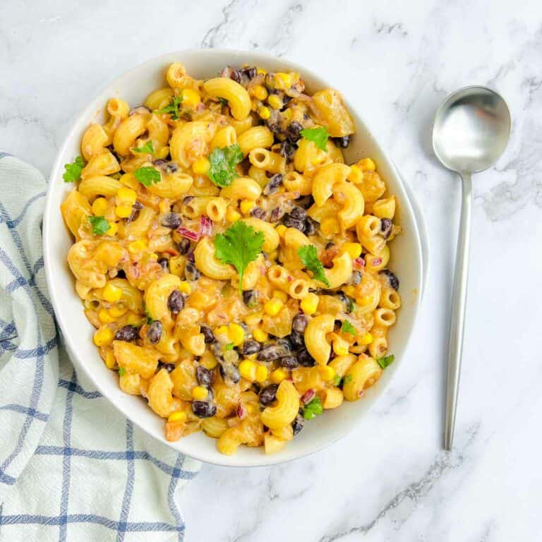 Mexican macaroni salad in a white bowl with a spoon in the background.