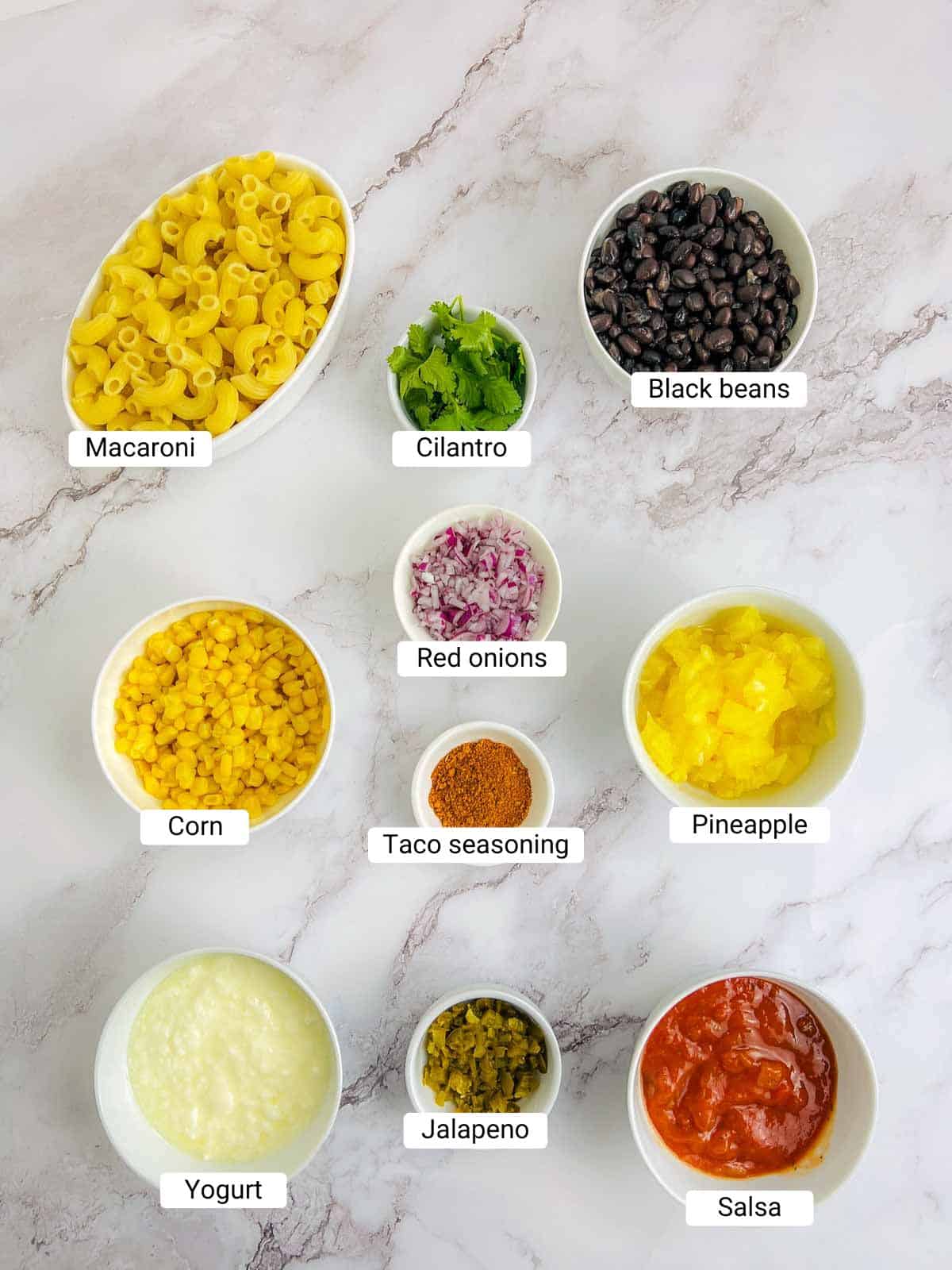Ingredients to make Mexican macaroni salad on a marble surface.